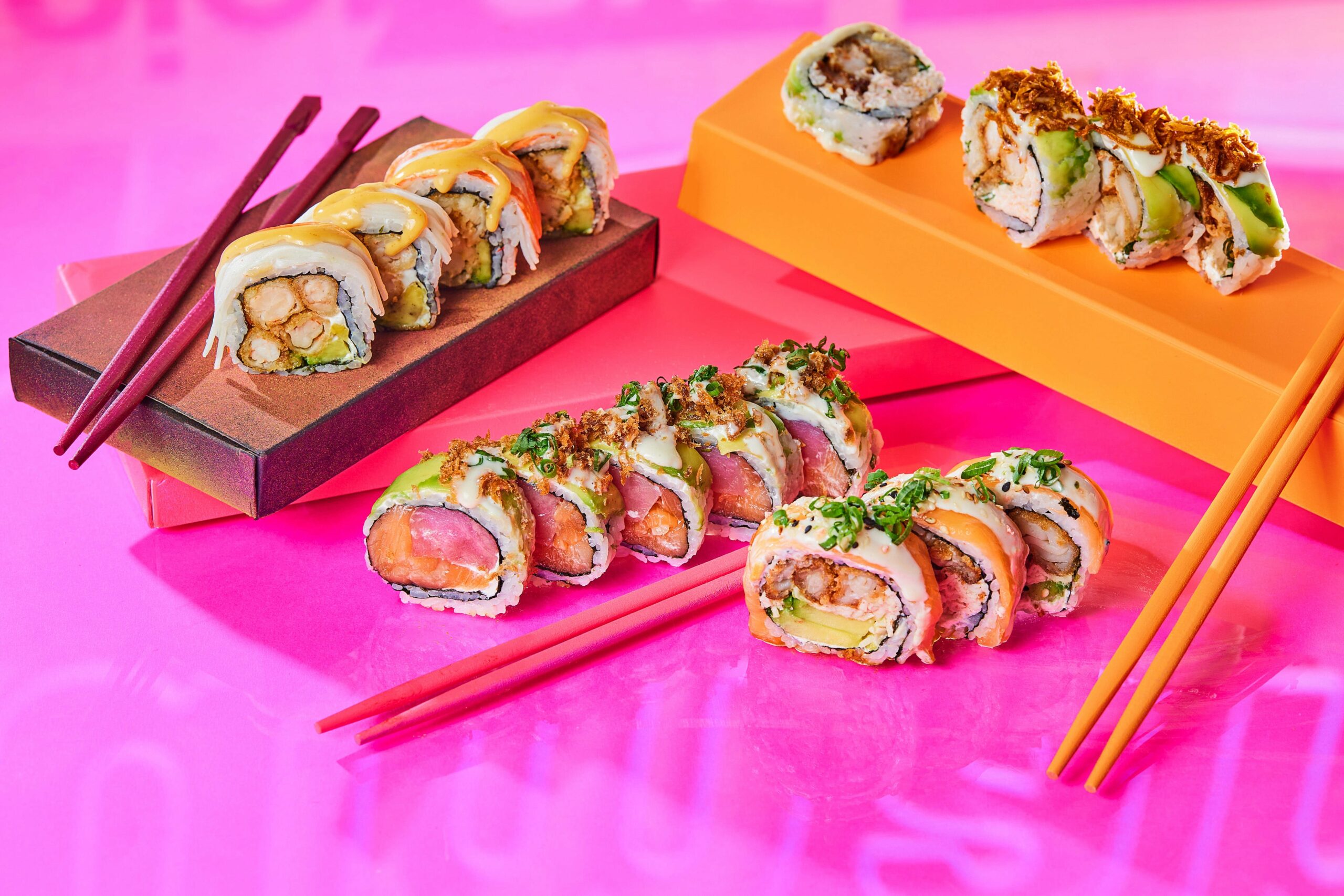 Variedad de rolls de sushi de Nacionsushi presentados en bases de colores con palillos, mostrando diferentes ingredientes y toppings.